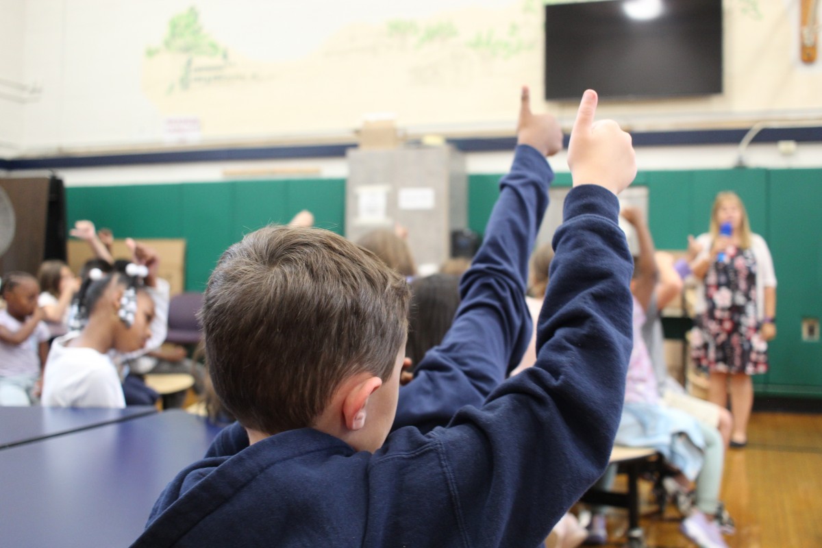 Students giving thumbs up at assembly